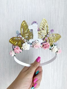 a hand holding a tiara with flowers and butterflies on it