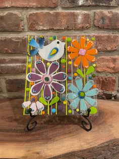 a bird sitting on top of a wooden table next to a flower and butterfly decoration