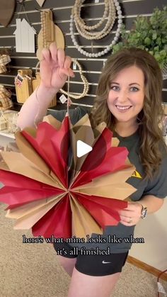 a woman holding up a large paper flower