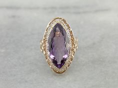 This vintage cocktail ring has lovely filigree details that make it suitable for a marquise cut amethyst. The openwork basket setting lets in plenty of light, while the four sturdy prongs hold even this large stone securely. This particular stone is fantastic! The color is deep true purple, with hints of raspberry, and the size and cut are extraordinary. Metal: 14K Yellow Gold Gem: Amethyst 10.75 Carats Gem Measurements: 23.5 x 11.7 mm, Marquise Cut Ring Size: 7.50 Marks: "14K" Stamped on the in Elegant Marquise Amethyst Ring With Prong Setting, Elegant Marquise Amethyst Ring, Elegant Marquise Cut Amethyst Ring, Elegant Marquise Amethyst Ring For Wedding, Fine Jewelry Amethyst Ring With Filigree For Formal Occasions, Formal Fine Jewelry Amethyst Ring With Filigree, Elegant Marquise Amethyst Wedding Ring, Ombre Rings, Amethyst Cocktail Ring