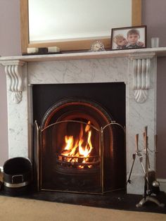 a fireplace with a fire in it and a mirror on the top shelf above it