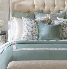 a bed with blue and white pillows on top of it