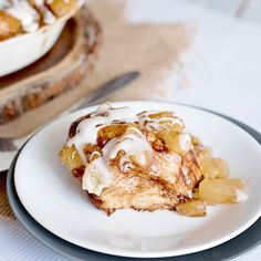 a white plate topped with food next to a bowl filled with fruit and covered in icing