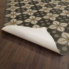 an area rug on the floor with a flower design in grey and white, laying on top of a hard wood floor