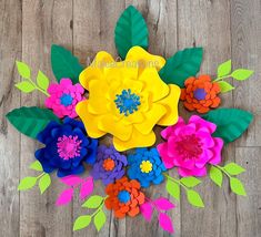 an arrangement of paper flowers sitting on top of a wooden floor