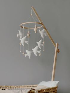 a baby crib with a white dove mobile hanging from it's side, next to a pillow