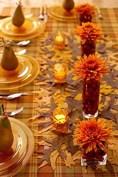 a table topped with plates and vases filled with flowers on top of a checkered table cloth