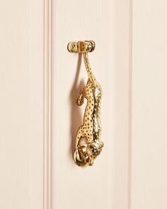 a door handle with a gold colored lizard on it's side hanging from a white door