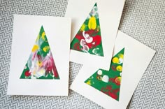 three christmas trees made out of paper on top of a white tablecloth with green and red paint