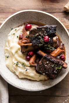 a bowl filled with meat and mashed potatoes topped with cranberries on top