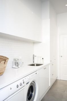 a washer and dryer in a small room with white walls, flooring and cabinets