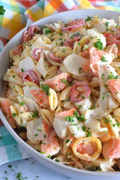 a white bowl filled with pasta salad on top of a checkered table cloth next to a fork