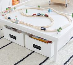 a toy train set on top of a white coffee table with storage drawers underneath it