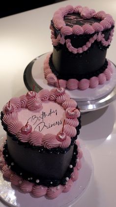 two heart shaped cakes sitting on top of plates covered in frosting and pink icing