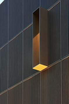 a clock on the side of a building with a yellow light in front of it