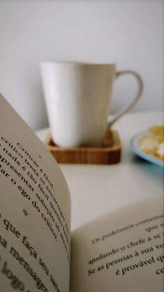 an open book sitting on top of a table next to a cup