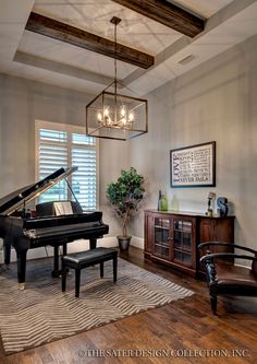 a living room with a grand piano in the center and a chandelier hanging from the ceiling