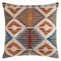 an orange, blue and brown pillow with diamond pattern on the front cover is sitting on a white surface