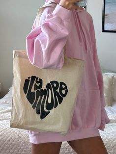 Show your love with this totally cute ILY MORE HEART TOTE! This trendy tote is made of 100% cotton and has a 6oz weight that’s perfect for carrying your everyday necessities. Plus, with its fun design, it’ll fill your heart (and your bag) with love! size: 22" handles 14 1/2" W x 15 1/2" H Fun Cotton Canvas Bag For Everyday, Olive Lynn, Dope Hoodies, Trendy Tote, Fun Design, Beach Bum, You Are Beautiful, You Bag, With Love