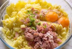 a bowl filled with meat and eggs on top of a table