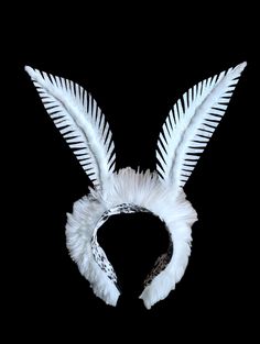 a white feathered headpiece on a black background with an animal print band around it