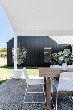 an outdoor dining area with white chairs and a wooden table