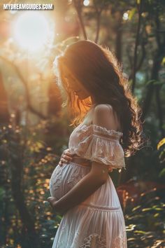 a pregnant woman standing in the woods at sunset