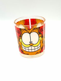 a candle holder with a cartoon character on the front and bottom, sitting on a white surface