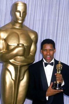 a man in a tuxedo holding an oscar statue and posing for the camera