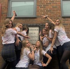 a group of young women standing next to each other in front of a brick building