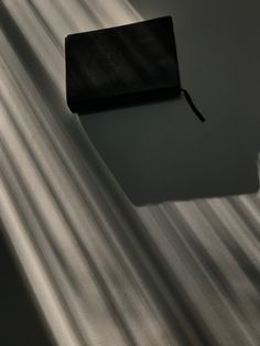 an empty black wallet sitting on top of a white sheeted floor with light coming through it