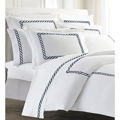 a bed with white sheets and blue trimmings on the pillowcase is shown