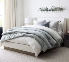 a bed with white sheets and pillows in a bedroom