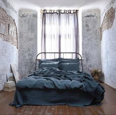 a bed sitting in a bedroom under a window next to a wooden floor and wall