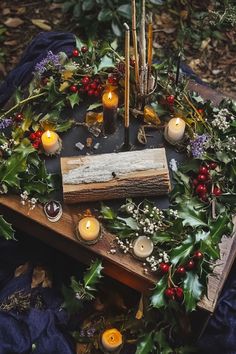 a wooden table topped with candles and greenery