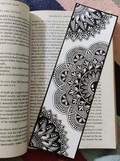 an open book with a black and white pattern on it next to an open bookmark