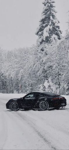 a black car driving down a snow covered road