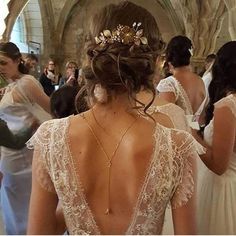 the back of a woman's wedding dress with gold leaves on her head and shoulders