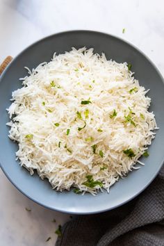 a blue bowl filled with white rice on top of a marble counter next to a gray towel