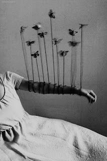 a woman laying in bed with her arms stretched out and flowers hanging from the ceiling