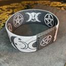 a black and white bracelet with pentagrams on it sitting on top of a rock