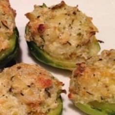 four stuffed green peppers on a white plate