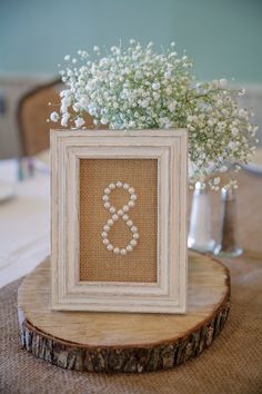 a white frame sitting on top of a table next to a vase filled with baby's breath