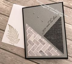 a close up of a card on a wooden surface with a leaf and brick pattern