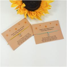 two sunflowers are sitting next to each other on a table with some cards