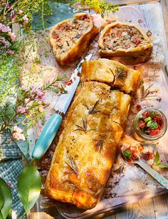 some food is laying out on a table with flowers and utensils next to it