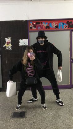 two people standing in front of a door with bags on their backs and one person wearing a face mask