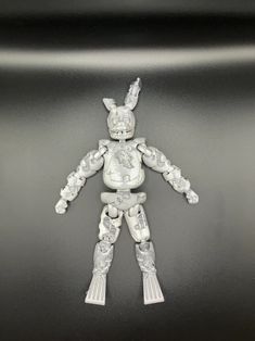 an action figure is shown on a black surface with white trimmings and silver accents