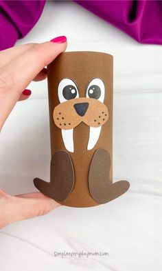 a hand holding up a brown paper cup with an animal face on it