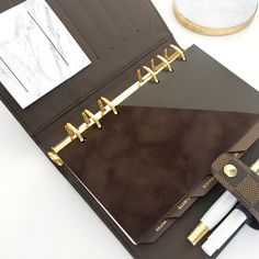 an open binder with two pens and a clipboard on the side next to it